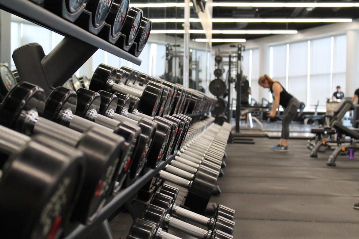 Person doing strength training workout at gym with dumbbells
